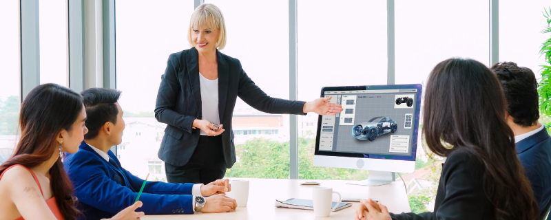Team discussing 2025 automotive market research with EV trends, luxury preferences, and consumer insights on a screen