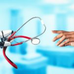 A robotic hand holding a stethoscope and reaching toward a human doctor’s hand, symbolizing the collaboration between AI technology and human empathy in healthcare research.